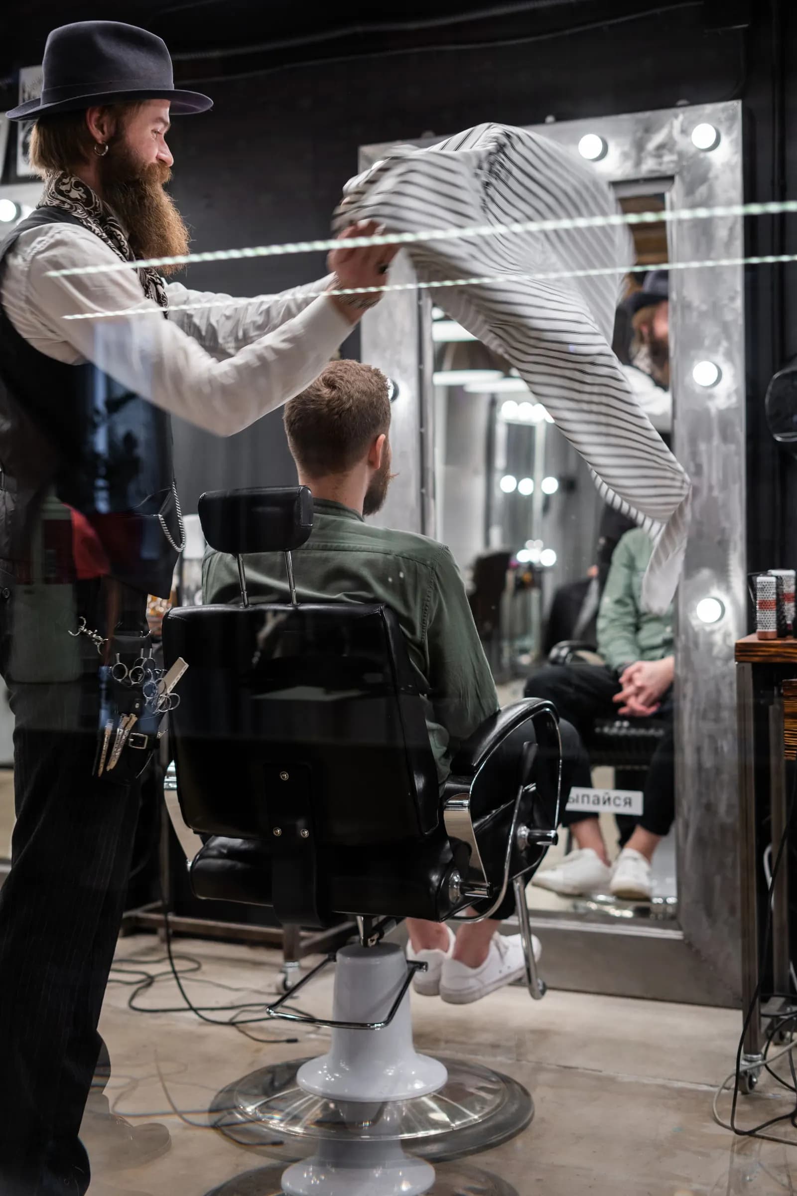 Barbero atendiendo a un cliente frente al espejo de una barbería