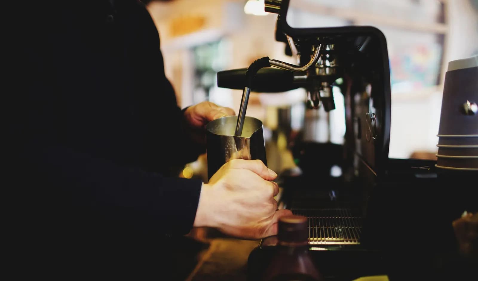 Barista espumando leche en la máquina de espresso de una cafetería